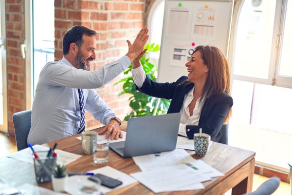 two business people high fiving after their winbacks campaign won