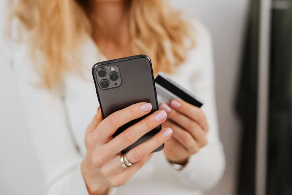Close up of woman holding mobile device and credit card.