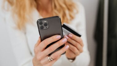 Close up of woman holding mobile device and credit card.