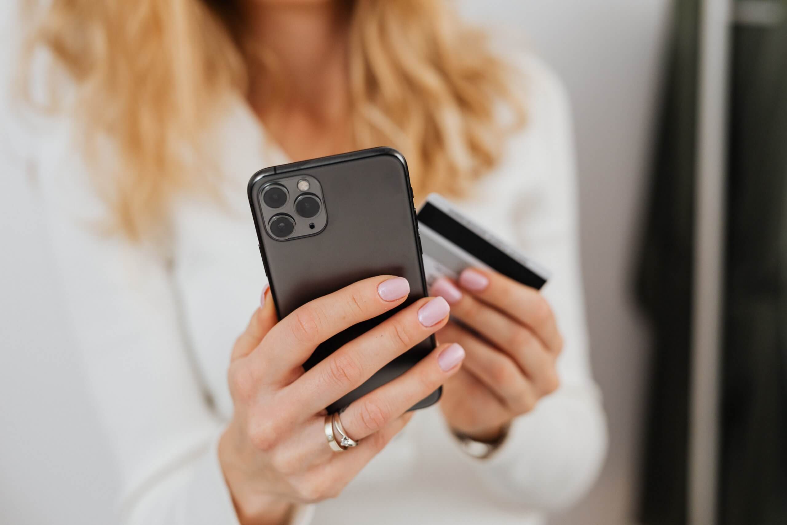 Close up of woman holding mobile device and credit card.