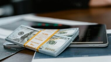 Bundles of money on top of mobile devices symbolize a successful monetization strategy.