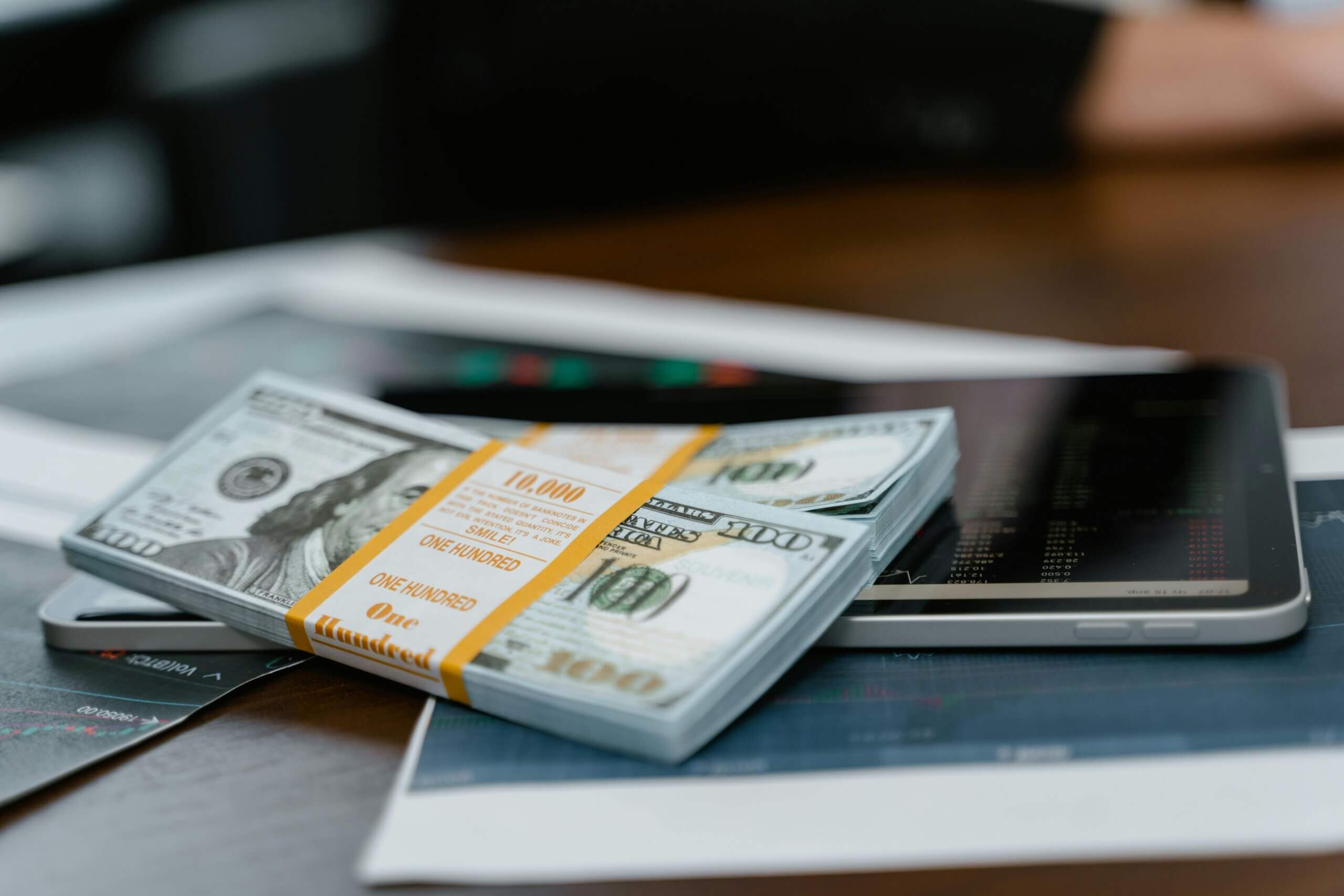 Bundles of money on top of mobile devices symbolize a successful monetization strategy.